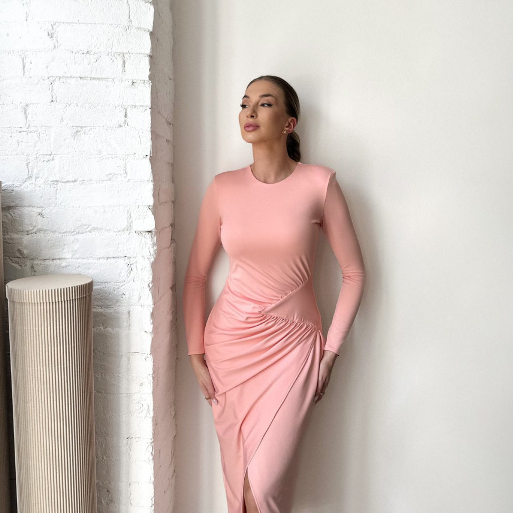 woman in light pink long sleeve bodycon dress standing near white wall woman in light pink long sleeve bodycon dress standing near white wall