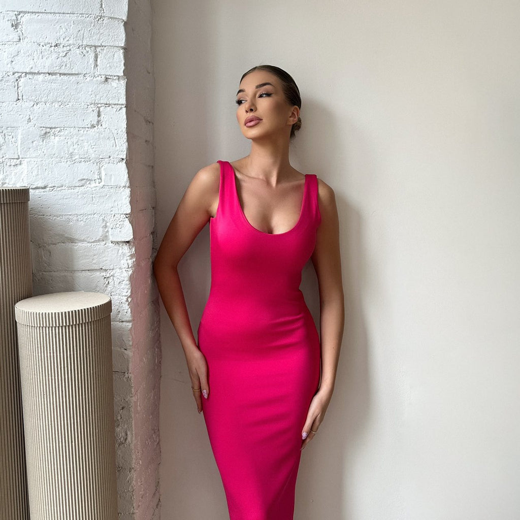 woman in pink bodycon dress standing against white wall woman in pink bodycon dress standing against white wall