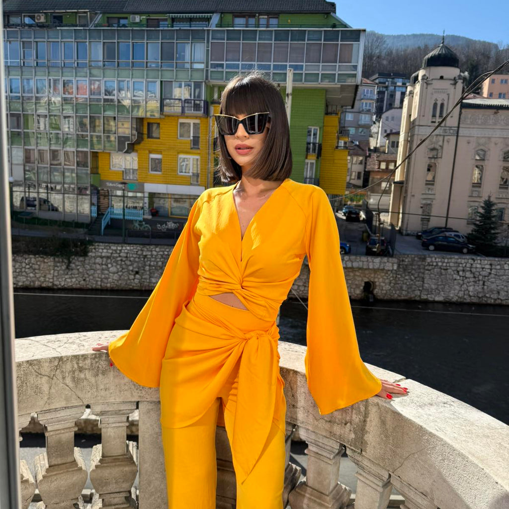 woman in yellow wrap top and pants outfit on balcony woman in yellow wrap top and pants outfit on balcony