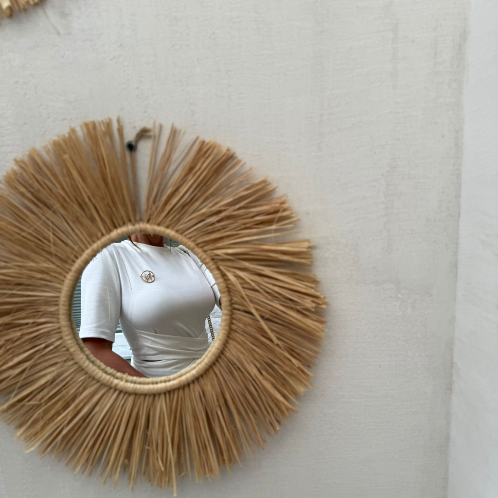 round mirror with woven straw frame reflecting white dress round mirror with woven straw frame reflecting white dress