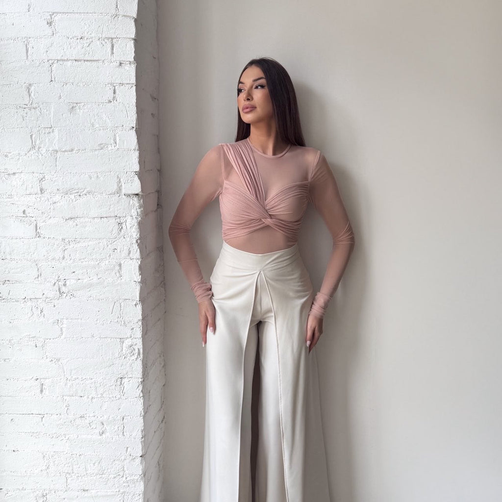 woman in pink top and white wide legged pants standing by brick wall woman in pink top and white wide legged pants standing by brick wall