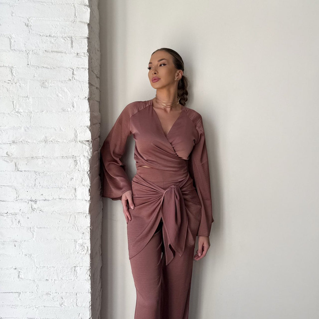 elegant woman wearing brown wrap dress against brick wall elegant woman wearing brown wrap dress against brick wall