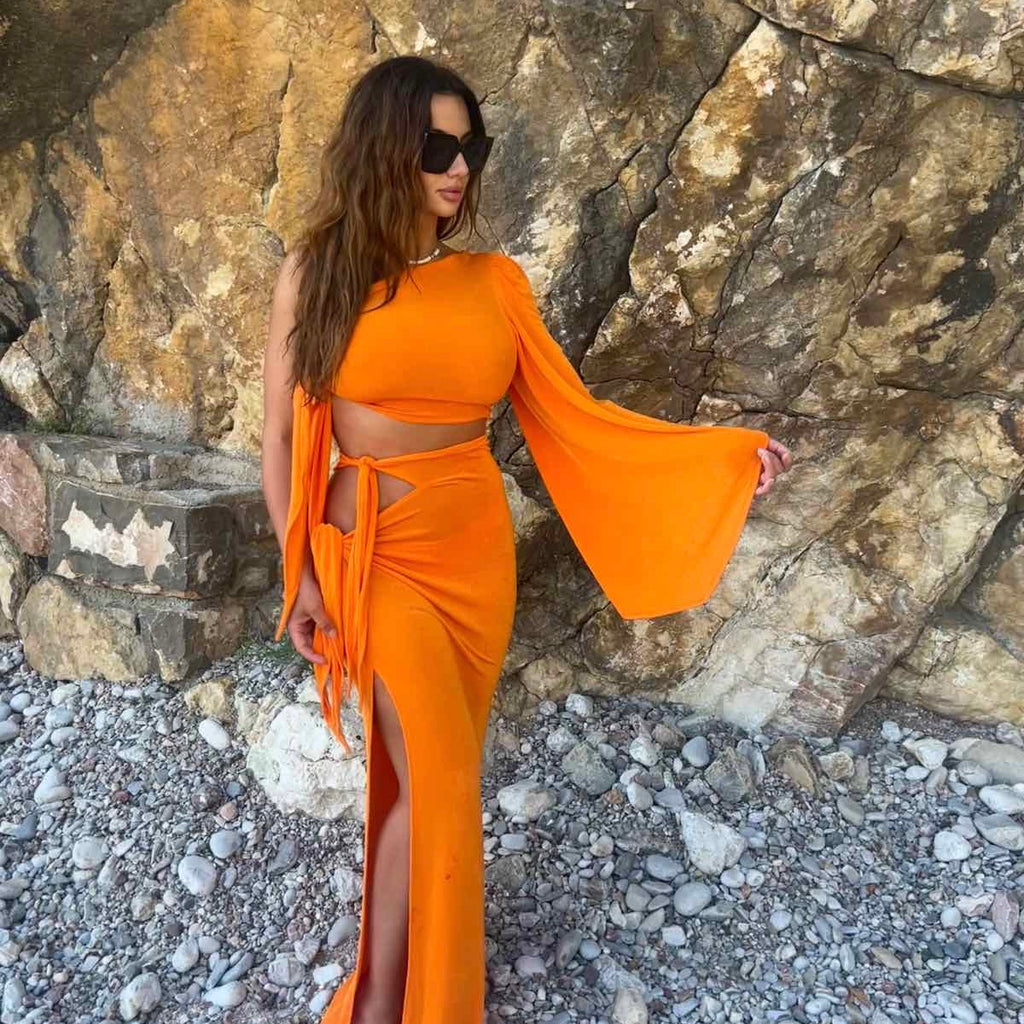 woman wearing bright orange maxi dress on rocky beach woman wearing bright orange maxi dress on rocky beach
