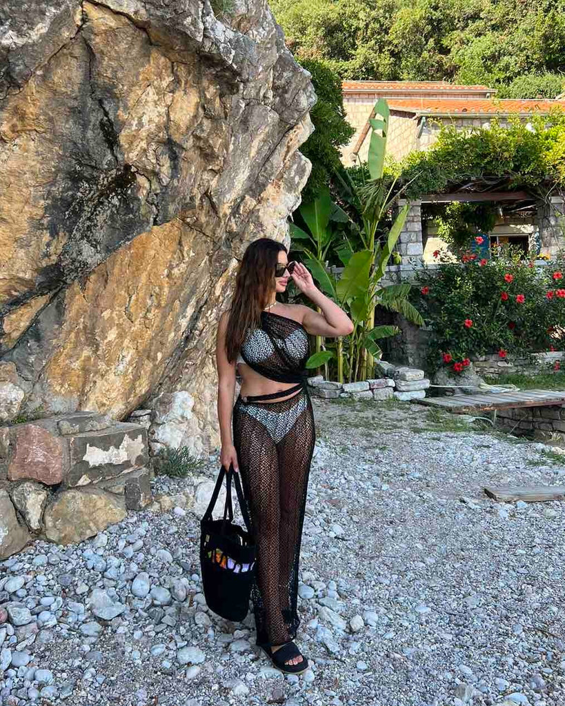 woman in mesh swimsuit coverup on rocky beach woman in mesh swimsuit coverup on rocky beach