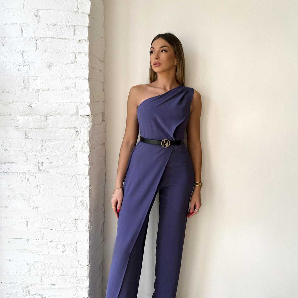 woman in purple one shoulder dress standing against white wall woman in purple one shoulder dress standing against white wall