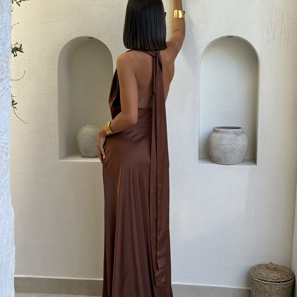 woman wearing brown halter dress with gold bracelet in stylish interior woman wearing brown halter dress with gold bracelet in stylish interior