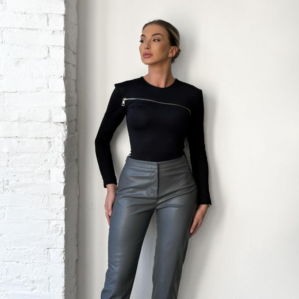 woman in black top and gray pants standing indoor woman in black top and gray pants standing indoor