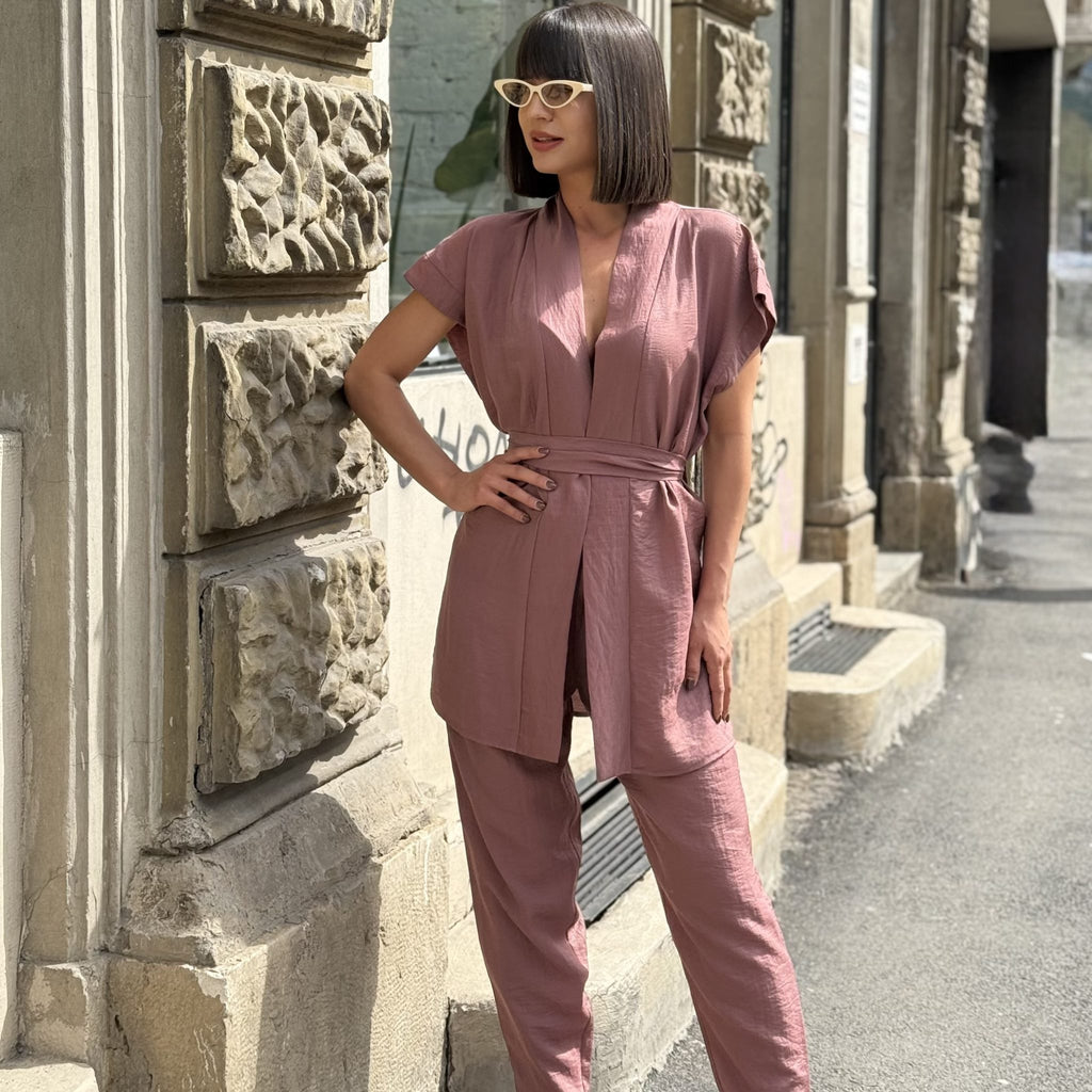 woman in pink jumpsuit and white sunglasses standing outside woman in pink jumpsuit and white sunglasses standing outside