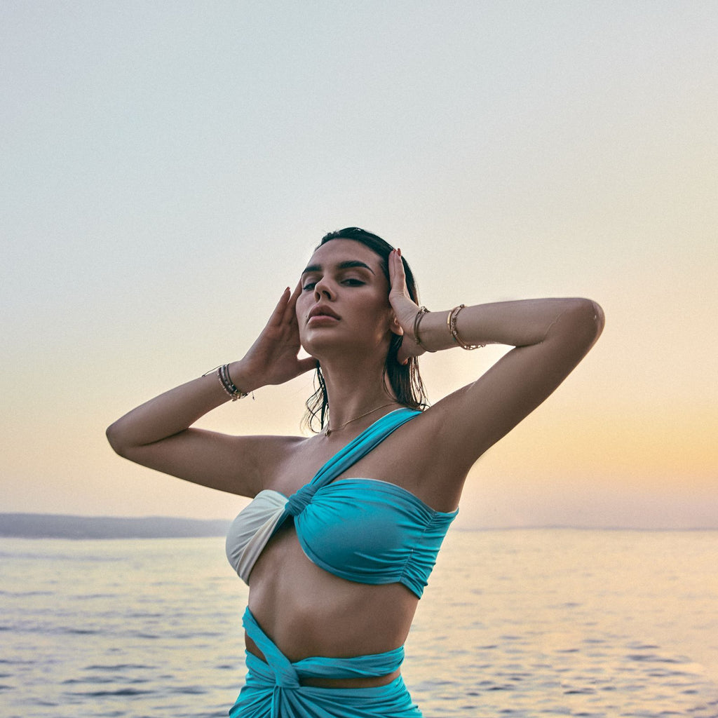 woman in blue cutout dress by water at sunset woman in blue cutout dress by water at sunset