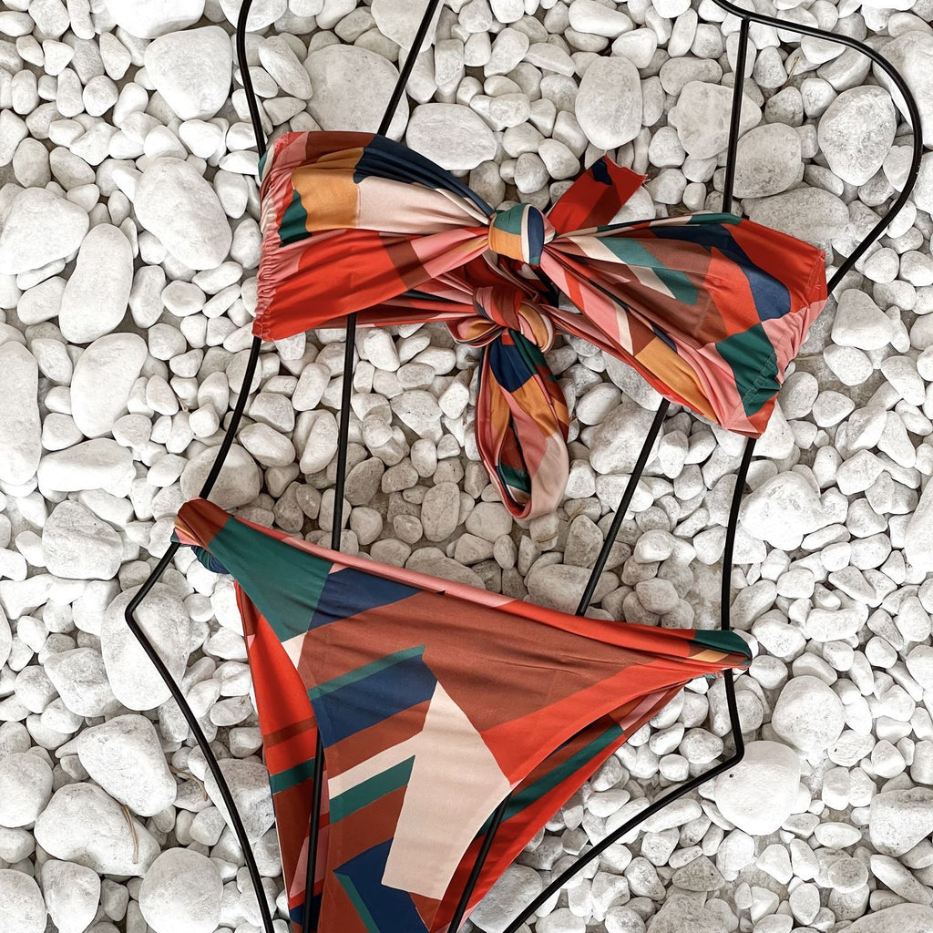 colorful abstract bikini top and bottom on white pebbles colorful abstract bikini top and bottom on white pebbles