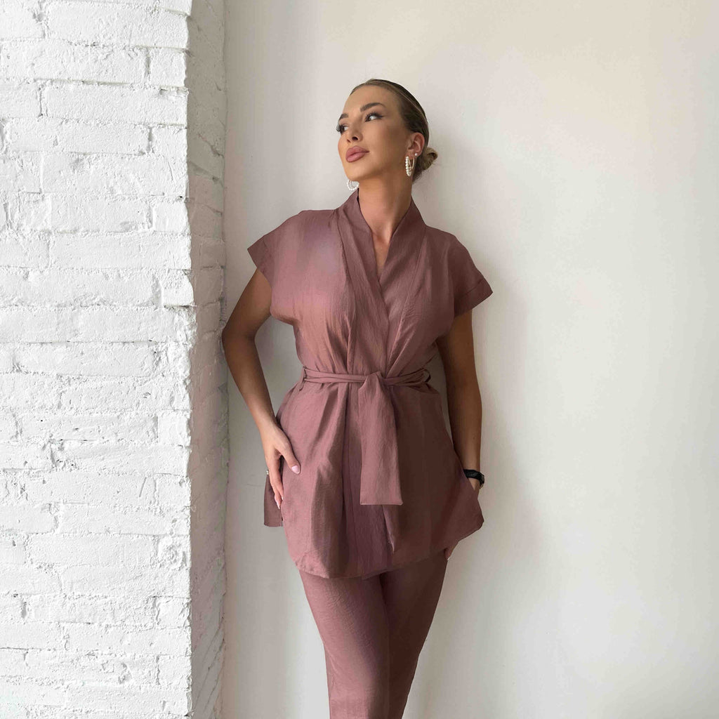 woman in pink wrap dress against white brick wall woman in pink wrap dress against white brick wall