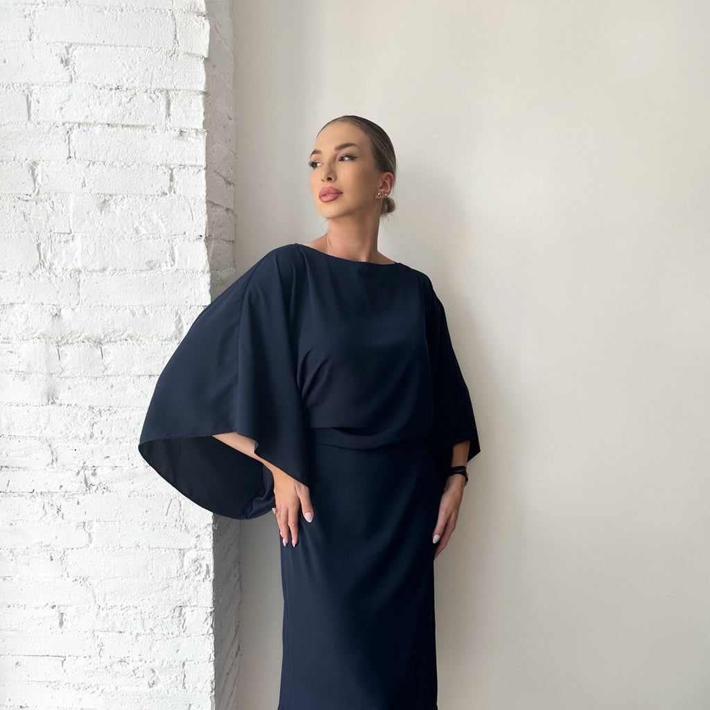 woman in navy dress standing against white brick wall woman in navy dress standing against white brick wall