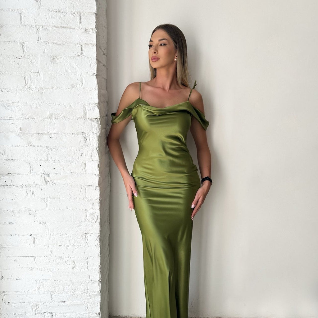 woman in green satin off shoulder dress standing by white brick wall woman in green satin off shoulder dress standing by white brick wall