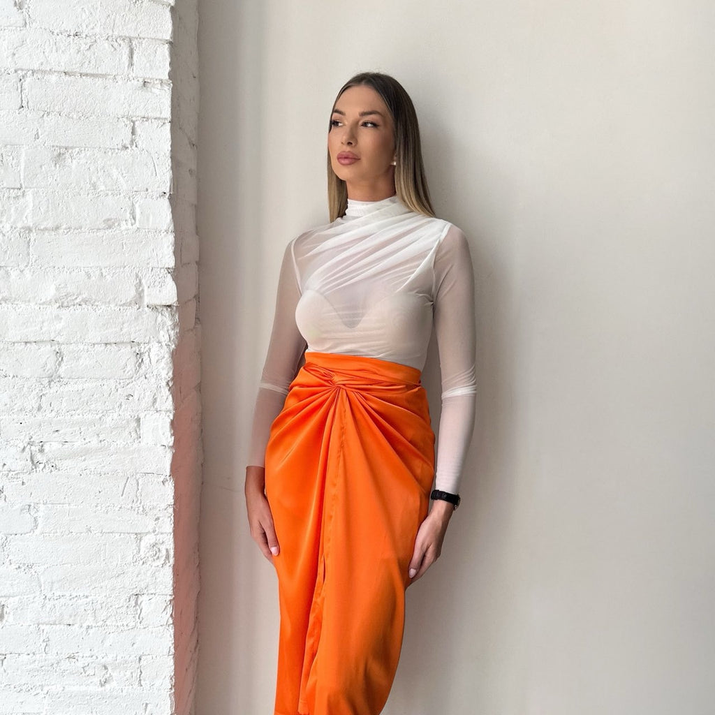 white top and orange skirt dress leaning against brick wall white top and orange skirt dress leaning against brick wall