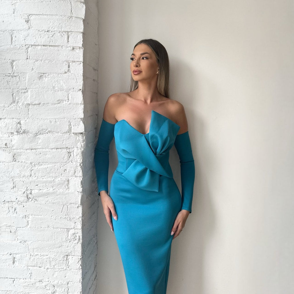 woman in blue off shoulder dress standing against white wall woman in blue off shoulder dress standing against white wall