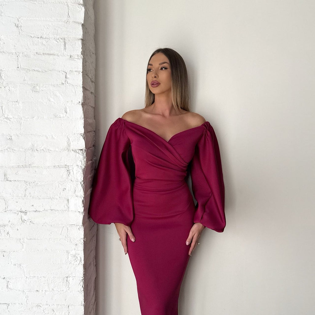 woman in off shoulder burgundy dress standing against brick wall woman in off shoulder burgundy dress standing against brick wall