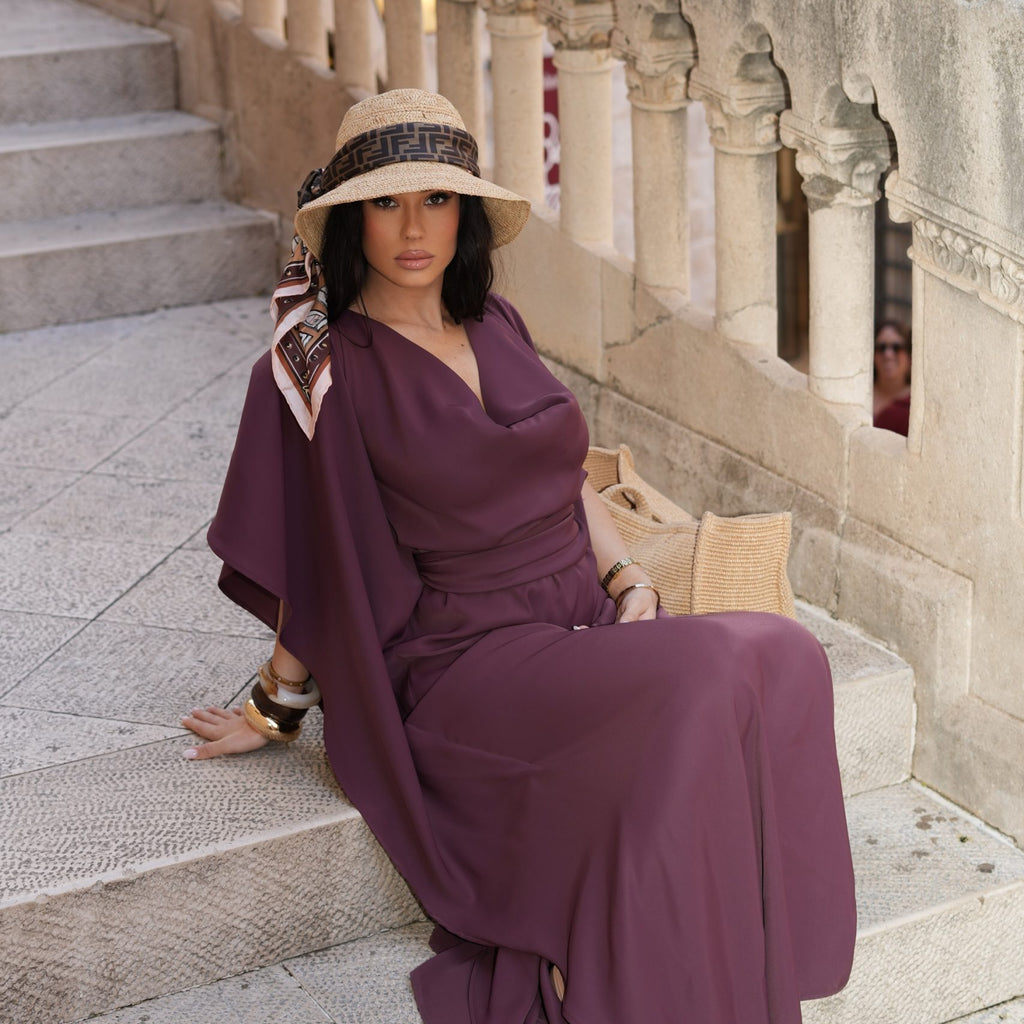 woman in violet maxi dress sitting on stone stairs wearing straw hat woman in violet maxi dress sitting on stone stairs wearing straw hat