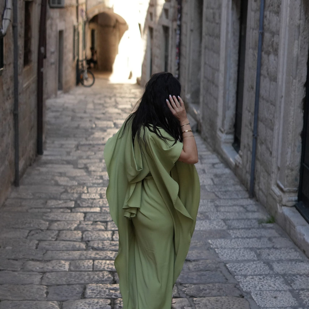 woman in green dress walking down cobbled street woman in green dress walking down cobbled street
