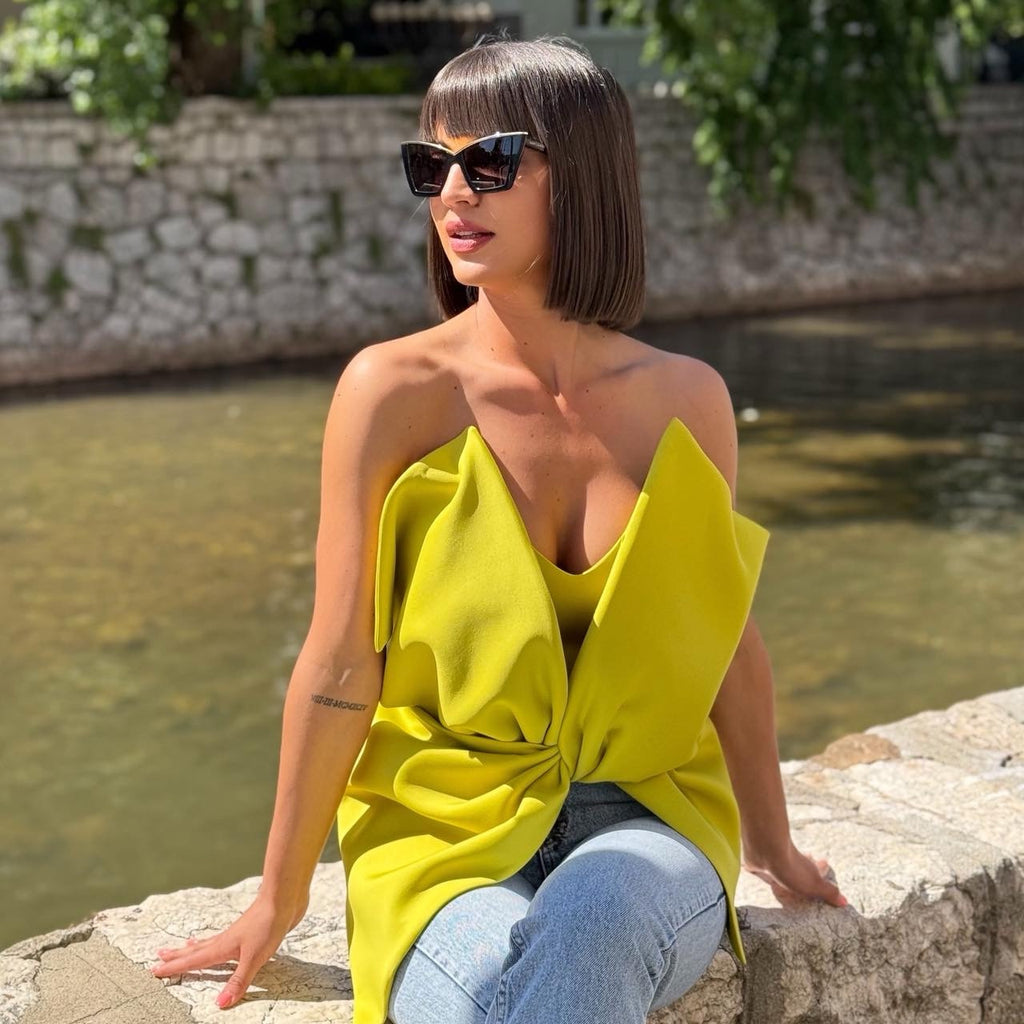 woman wearing yellow dress and jeans sitting near river in sunglasses woman wearing yellow dress and jeans sitting near river in sunglasses