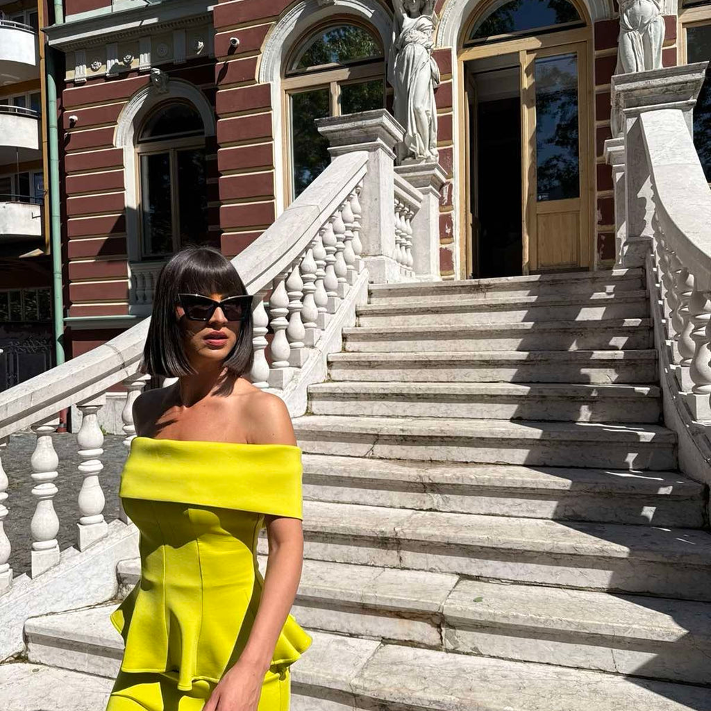 woman in bright yellow off the shoulder dress on stone steps woman in bright yellow off the shoulder dress on stone steps