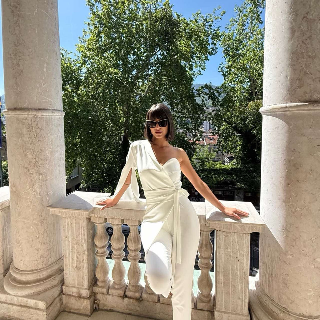 woman in white one shoulder jumpsuit outdoor balcony scene woman in white one shoulder jumpsuit outdoor balcony scene