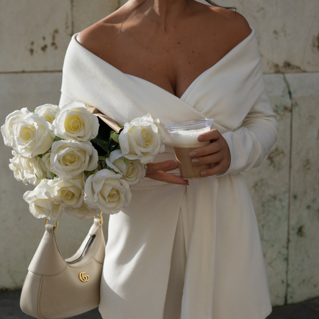 woman in off shoulder white dress holding coffee and bouquet of roses woman in off shoulder white dress holding coffee and bouquet of roses