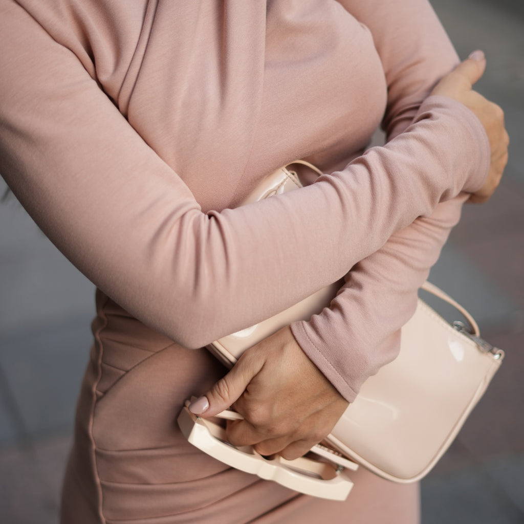 woman wearing pink dress holding beige handbag woman wearing pink dress holding beige handbag