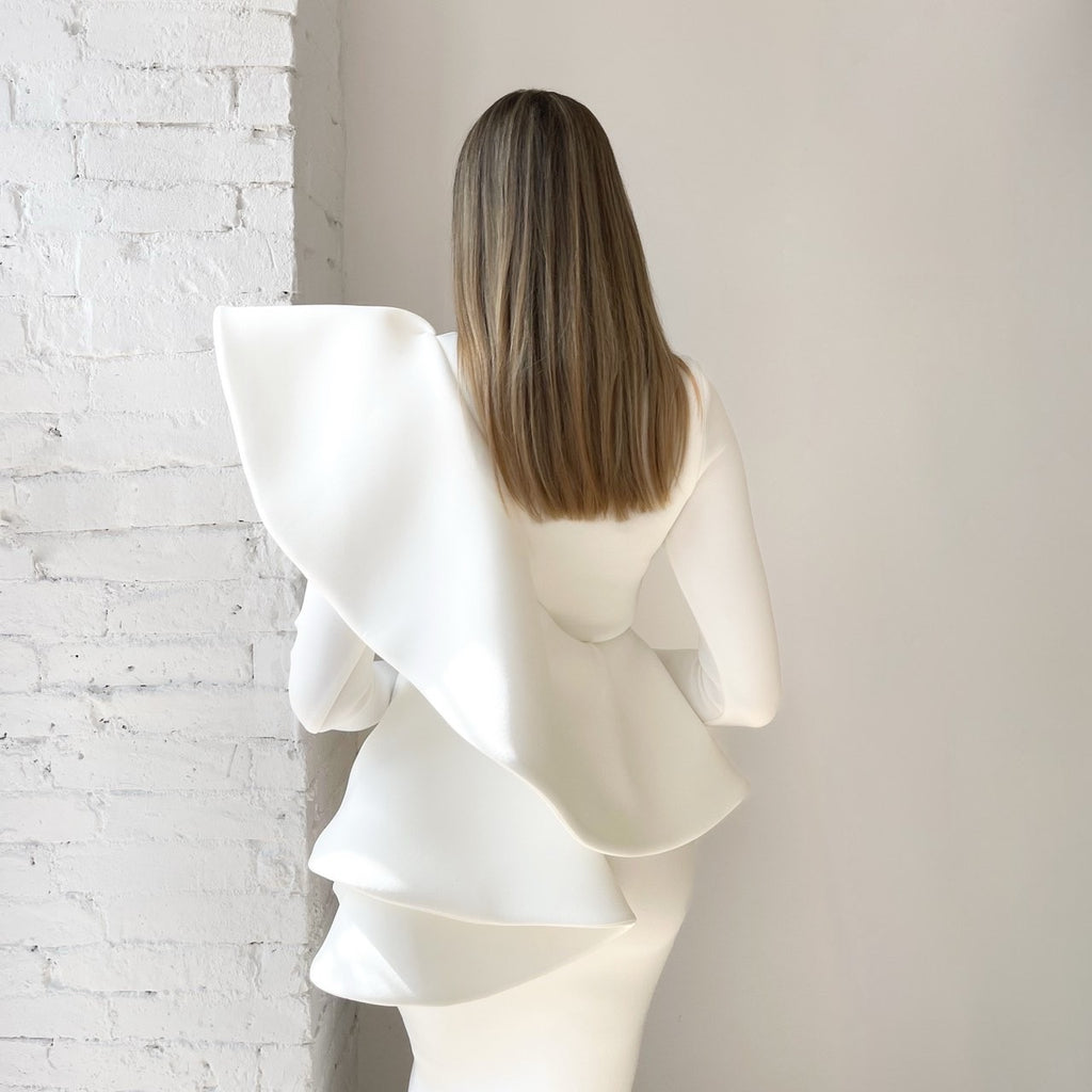 white ruffled dress back view against white brick wall white ruffled dress back view against white brick wall
