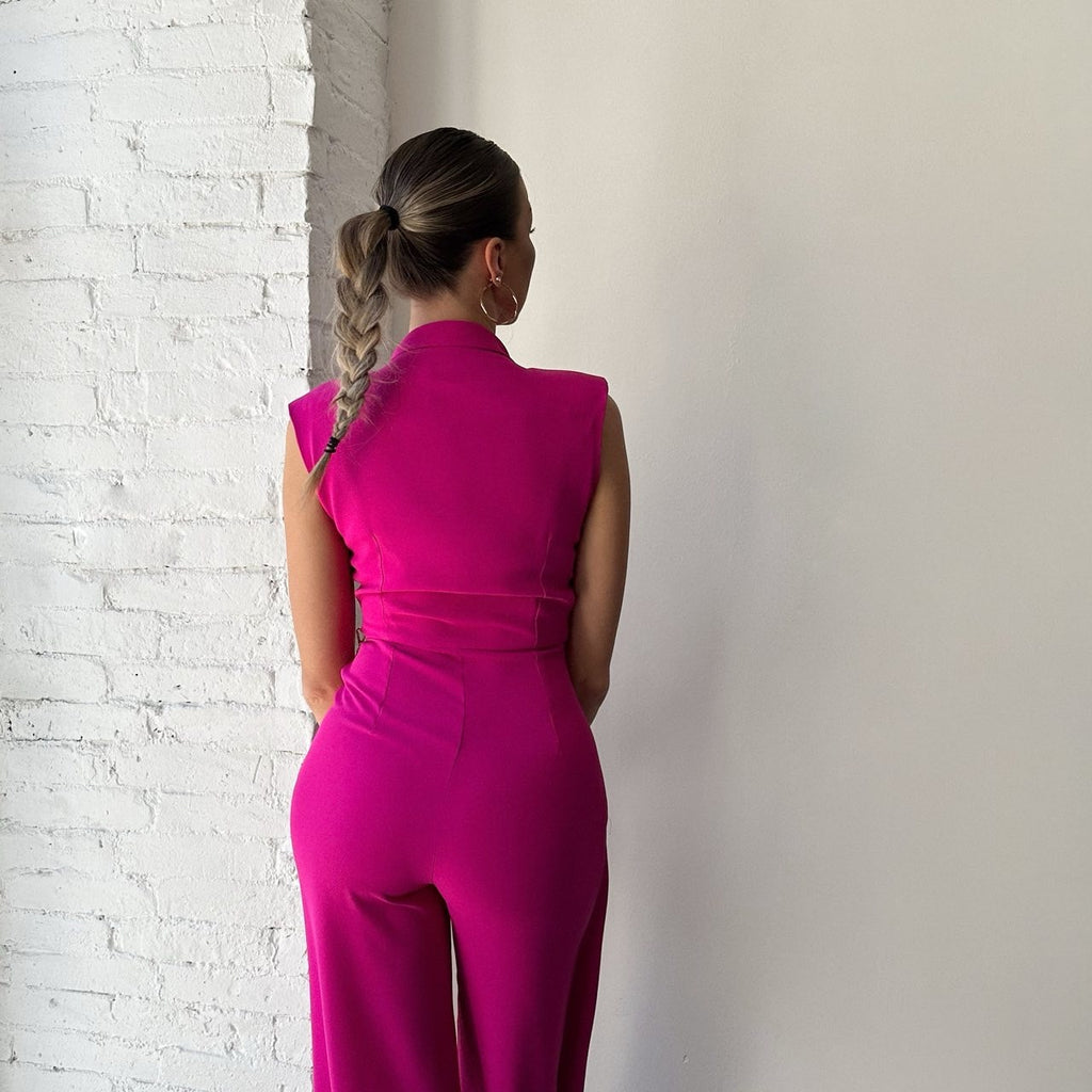 woman in pink sleeveless jumpsuit standing near white brick wall woman in pink sleeveless jumpsuit standing near white brick wall