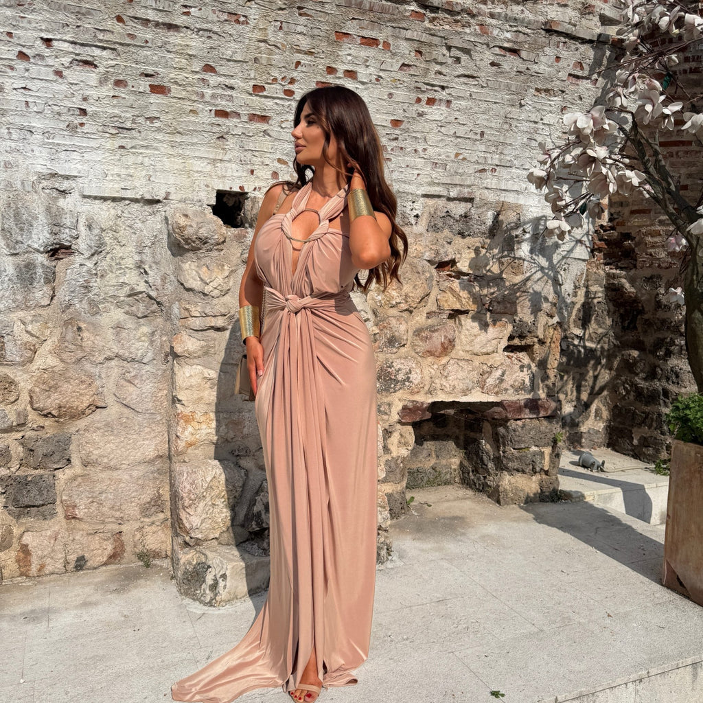 woman in elegant blush dress standing against stone wall woman in elegant blush dress standing against stone wall