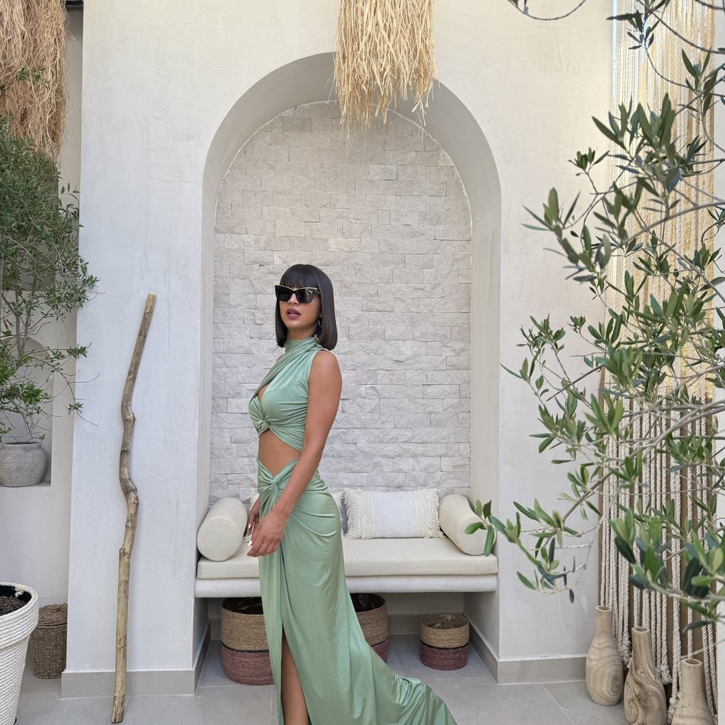 woman wearing green cutout dress and sunglasses standing in stylish room woman wearing green cutout dress and sunglasses standing in stylish room