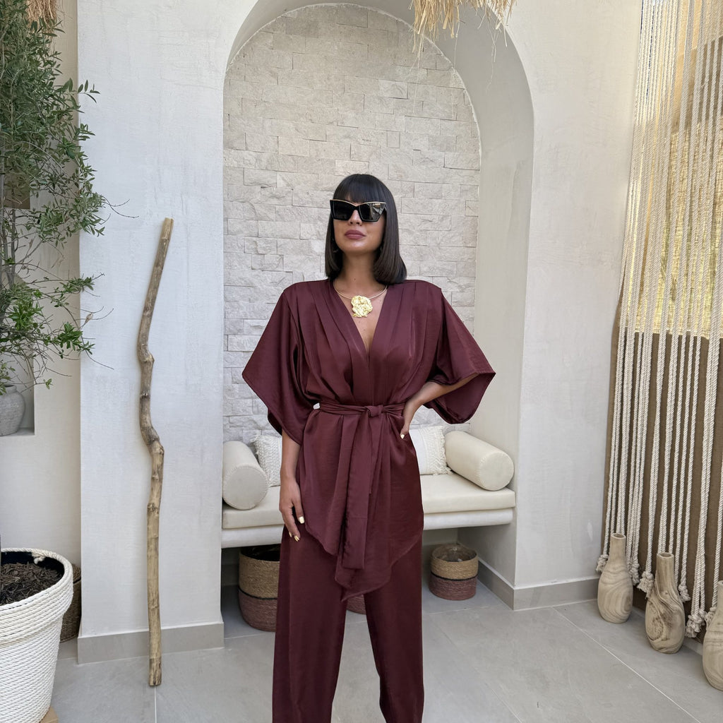 woman in burgundy kimono jumpsuit standing in modern room woman in burgundy kimono jumpsuit standing in modern room