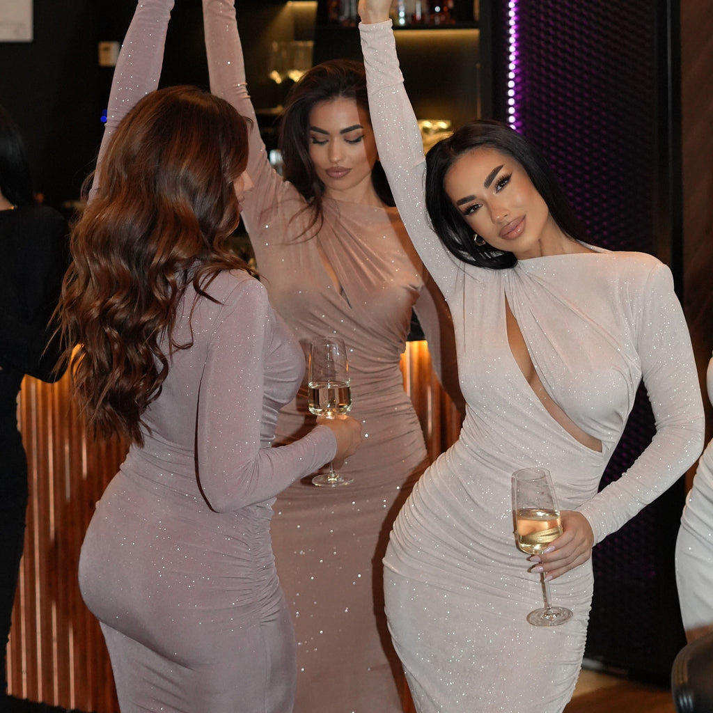 women in glittery dresses holding wine glasses at party women in glittery dresses holding wine glasses at party
