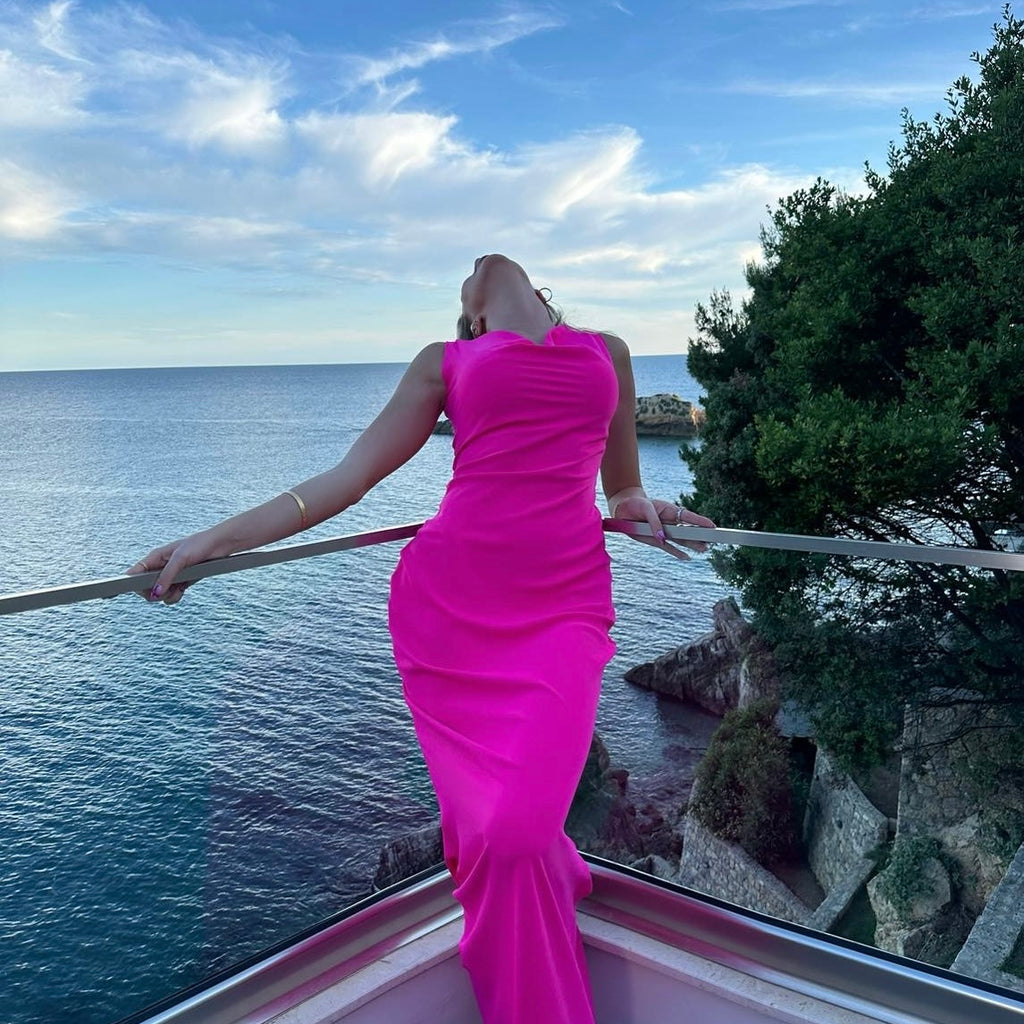woman in pink dress standing on balcony with sea view woman in pink dress standing on balcony with sea view