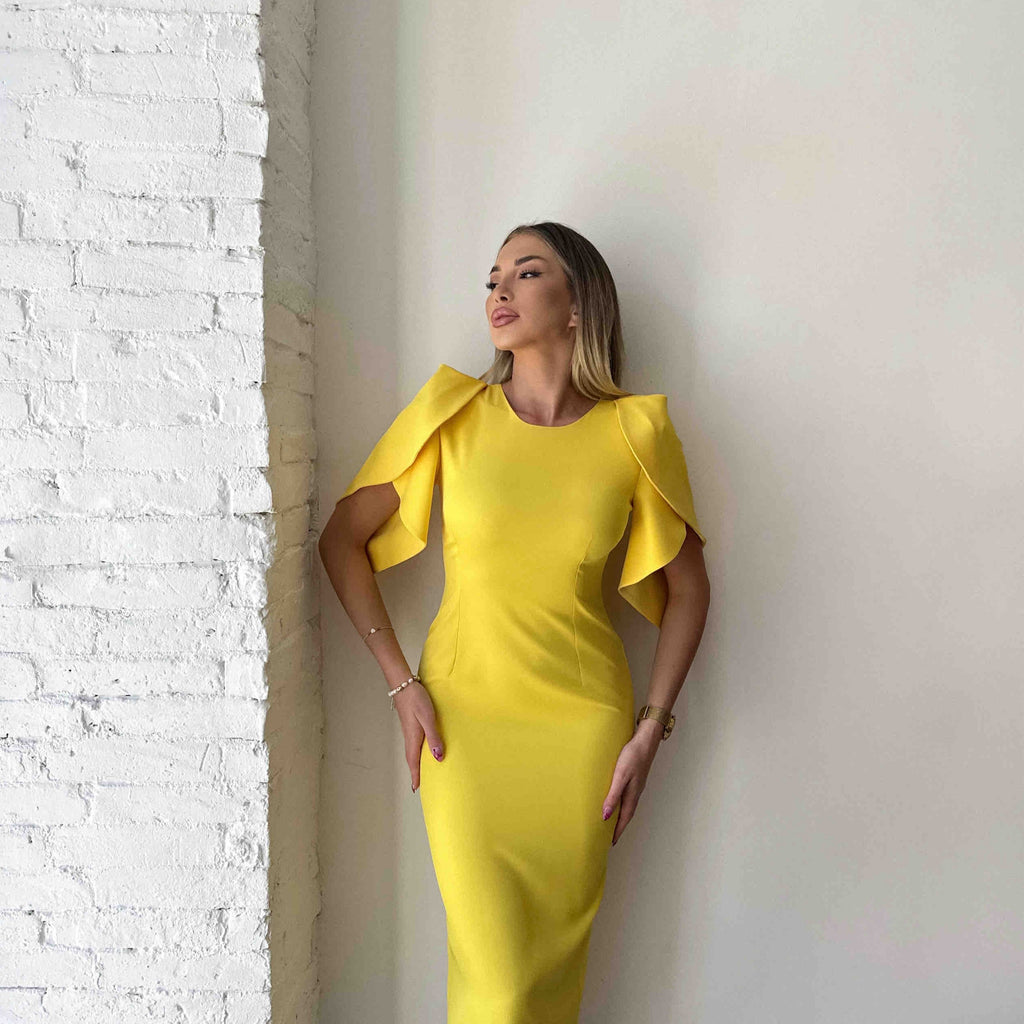woman in yellow ruffle sleeve dress against brick wall woman in yellow ruffle sleeve dress against brick wall