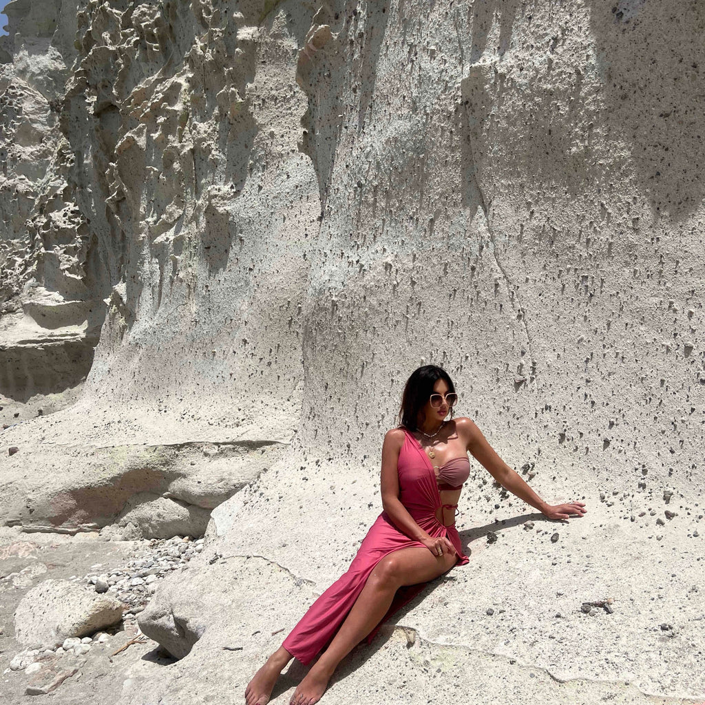 woman in pink dress sitting on rocky landscape woman in pink dress sitting on rocky landscape