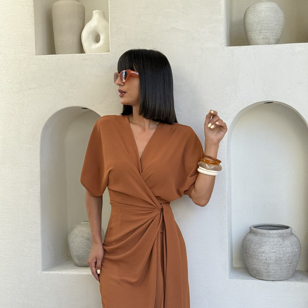 woman wearing rust colored wrap dress with shelf decor background woman wearing rust colored wrap dress with shelf decor background
