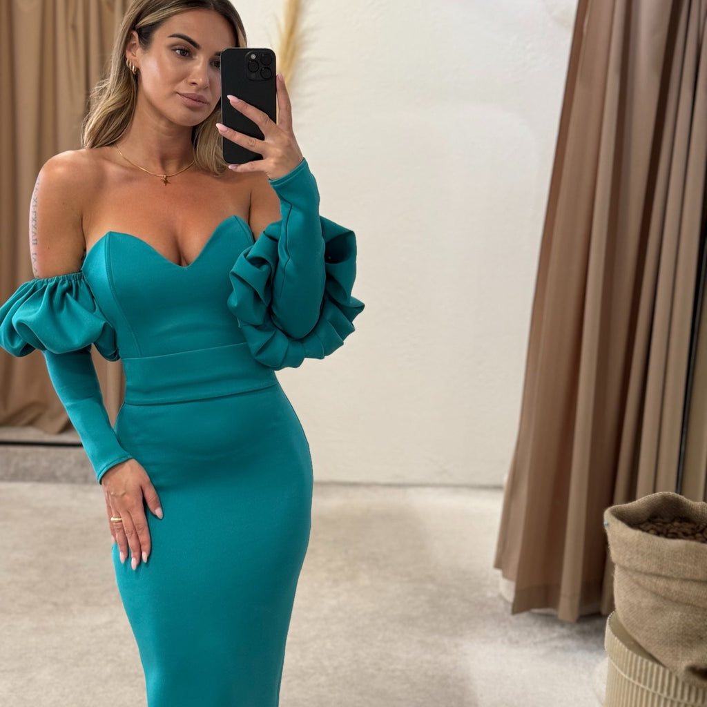 woman wearing teal off shoulder dress in fitting room woman wearing teal off shoulder dress in fitting room