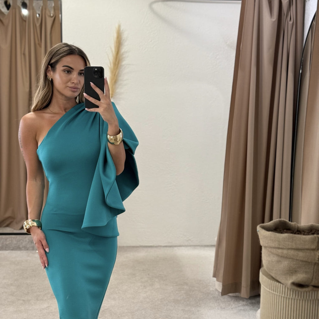 woman in teal one shoulder dress in dressing room woman in teal one shoulder dress in dressing room