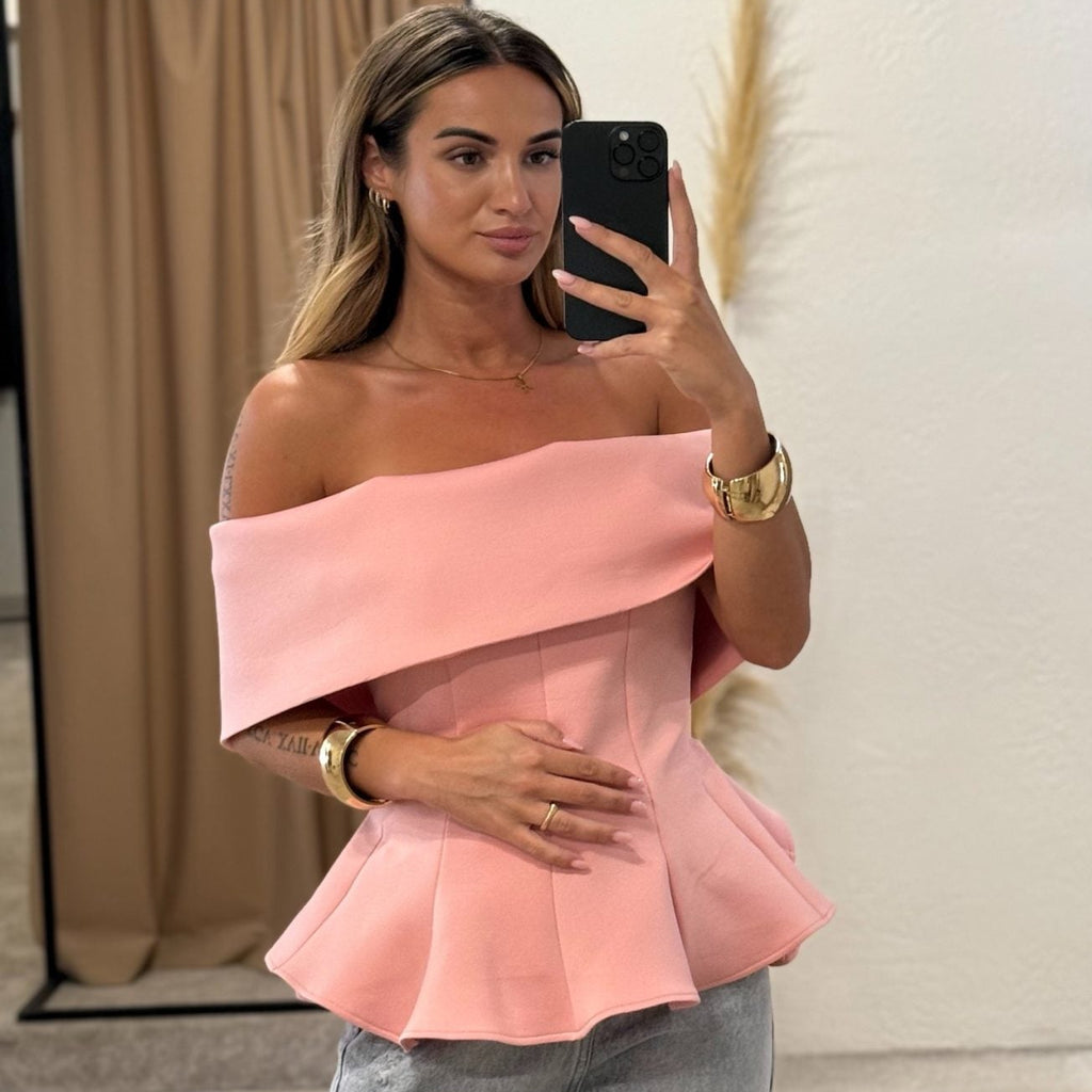 woman wearing pink off shoulder top and jeans in fitting room woman wearing pink off shoulder top and jeans in fitting room