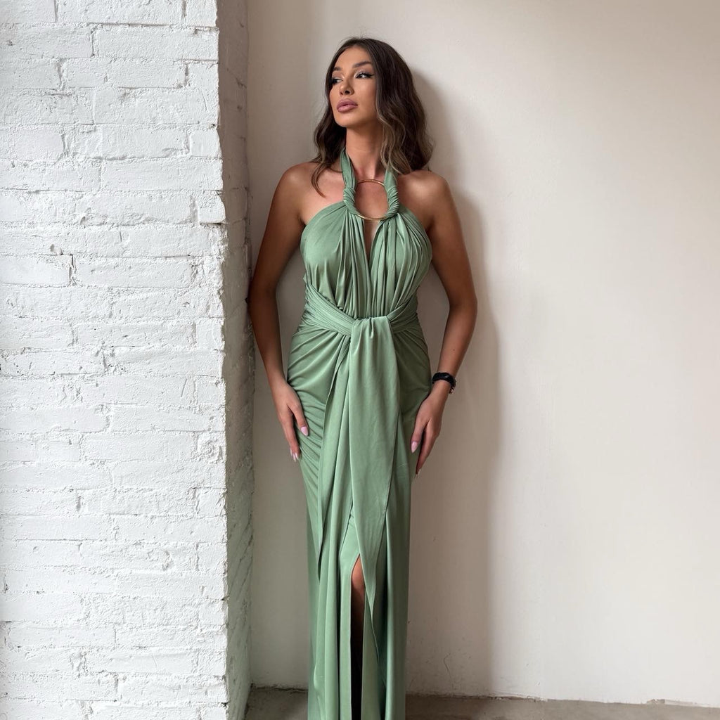 woman in green halter dress standing against brick wall woman in green halter dress standing against brick wall