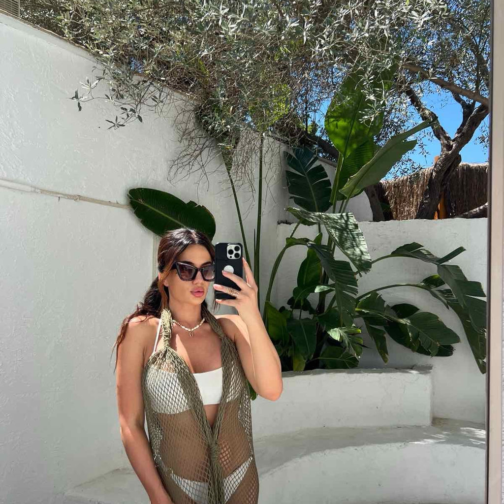 model in white bikini and mesh cover up taking selfie in garden model in white bikini and mesh cover up taking selfie in garden