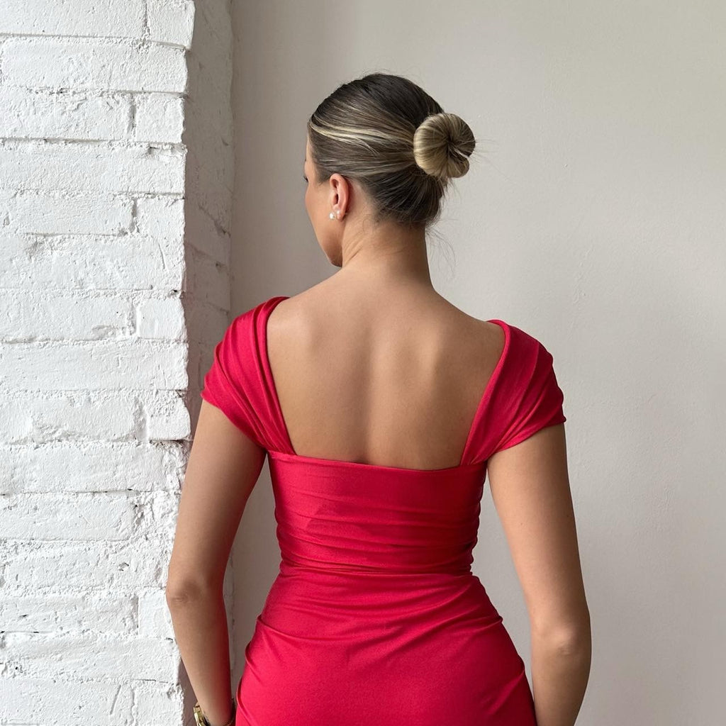 woman in red backless dress facing brick wall woman in red backless dress facing brick wall