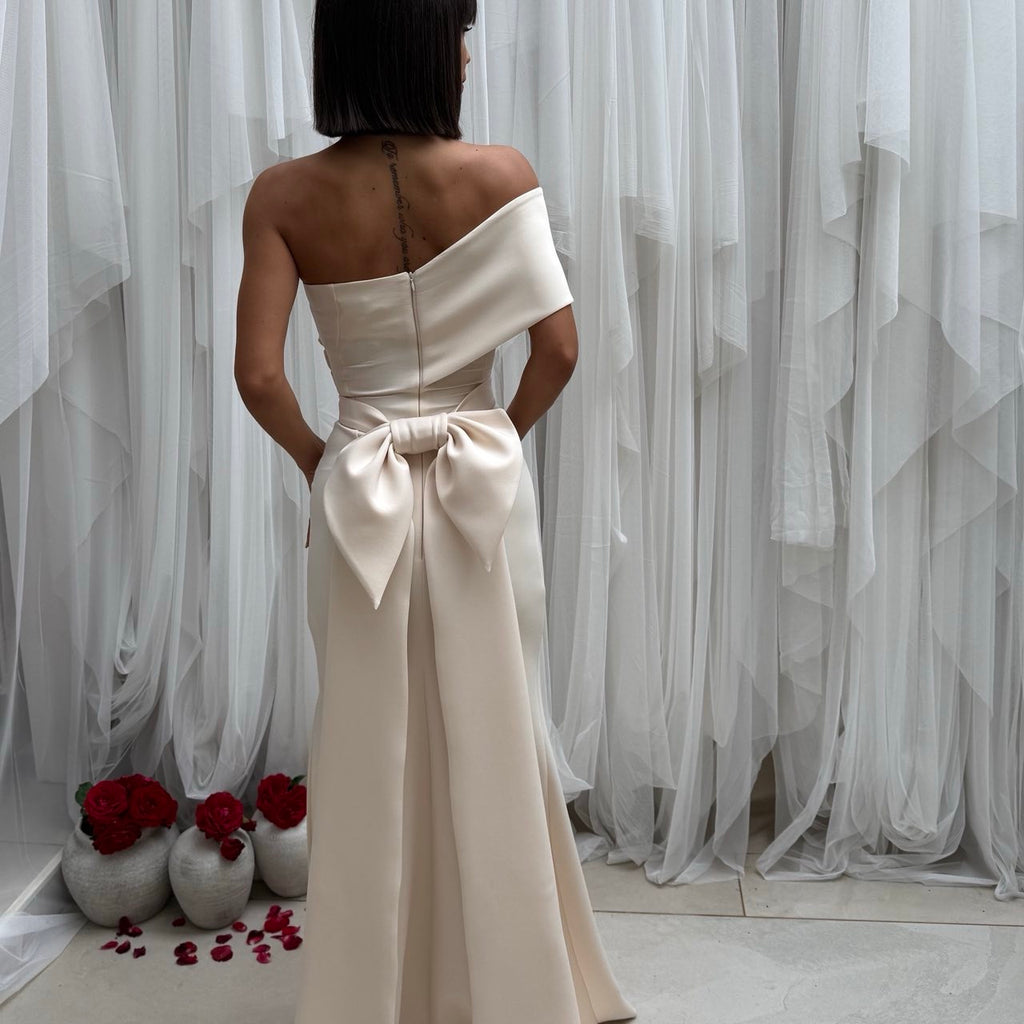 woman in elegant off shoulder cream dress with large bow back woman in elegant off shoulder cream dress with large bow back