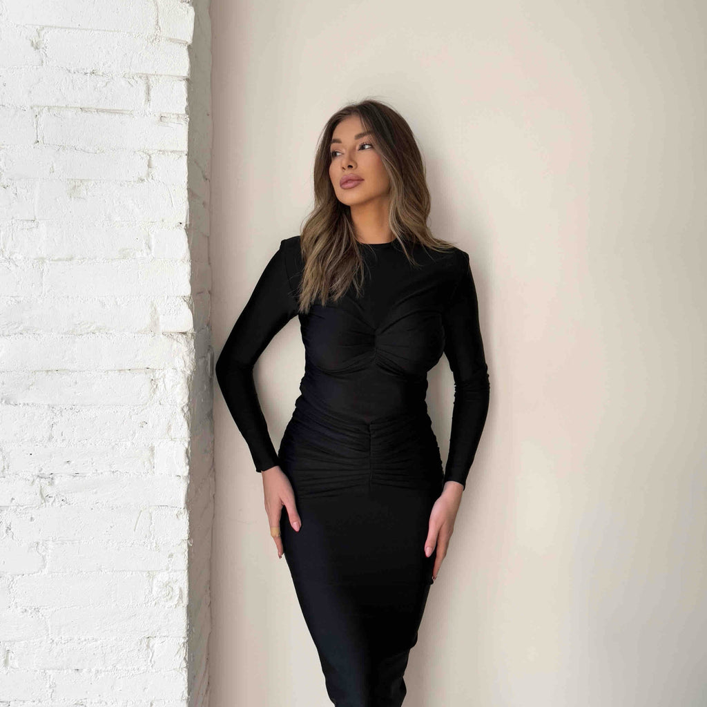 black long sleeve midi dress against white brick wall black long sleeve midi dress against white brick wall