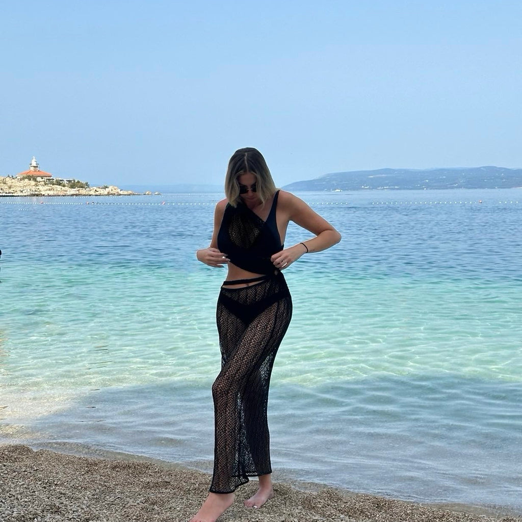 woman in black beach coverup on pebbly shore woman in black beach coverup on pebbly shore