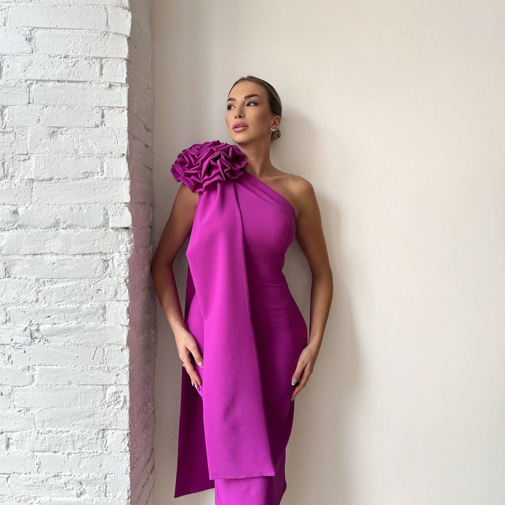 woman in pink one shoulder dress standing against brick wall woman in pink one shoulder dress standing against brick wall