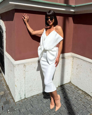 woman in elegant white dress with large bow detail standing outside
