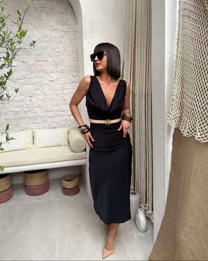 woman wearing a black dress with white belt and sunglasses indoors