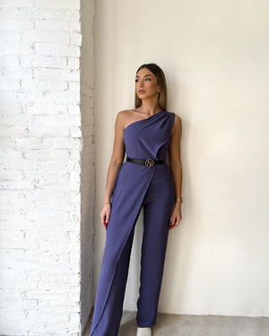 woman in purple one shoulder dress standing against white wall